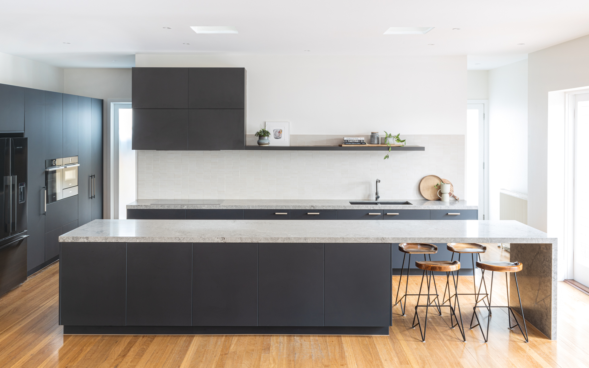 Modern Elwood kitchen renovation in Polytec matt black melamine with Caesarstone Turbine Grey stone benchtop and textured splashback tile