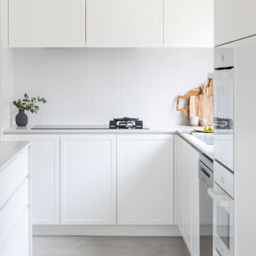 Shaker style kitchen in white with white bench tops & white tiled splashback