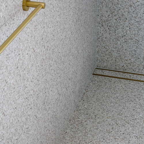 Brushed brass tile insert strip drain with terrazzo tiles