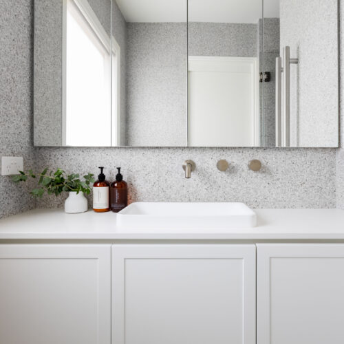 Custom shaker vanity unit with stone benchtop in white against grey terrazzo wall tiles
